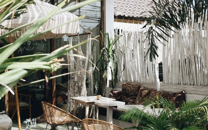 white table with brown wicker chair beside plants