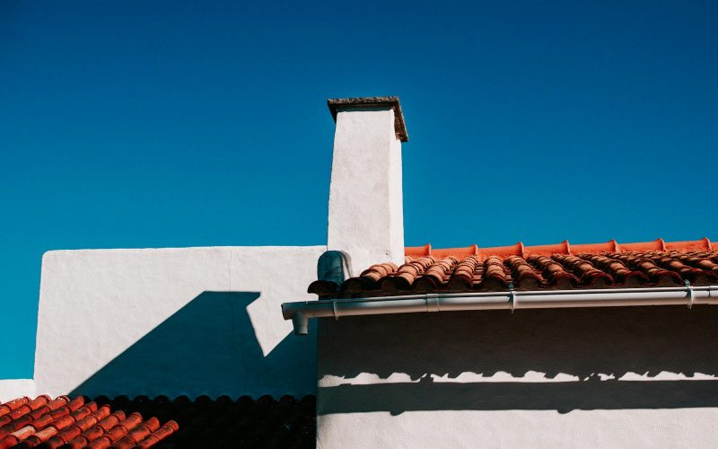 Low angle view of a traditional terracotta rooftop under a clear blue sky in summer.
