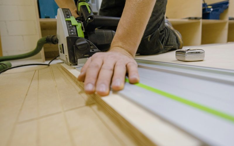 person in gray t-shirt holding green and white plastic tool